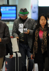 组图：徐峥戴绿边帽独自回京 把玩手机目光呆滞