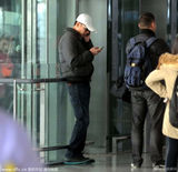 组图：刘烨现身机场难忍烟瘾 带两手机似业务忙