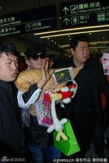 组图：李准基现身机场遭围堵 熊猫公仔遮面调皮卖萌